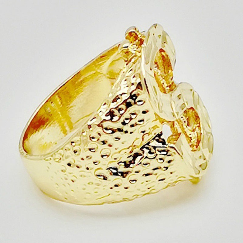Gold-tone hip hop ring with a textured finish and a prominent dollar sign design, captured from a side angle.