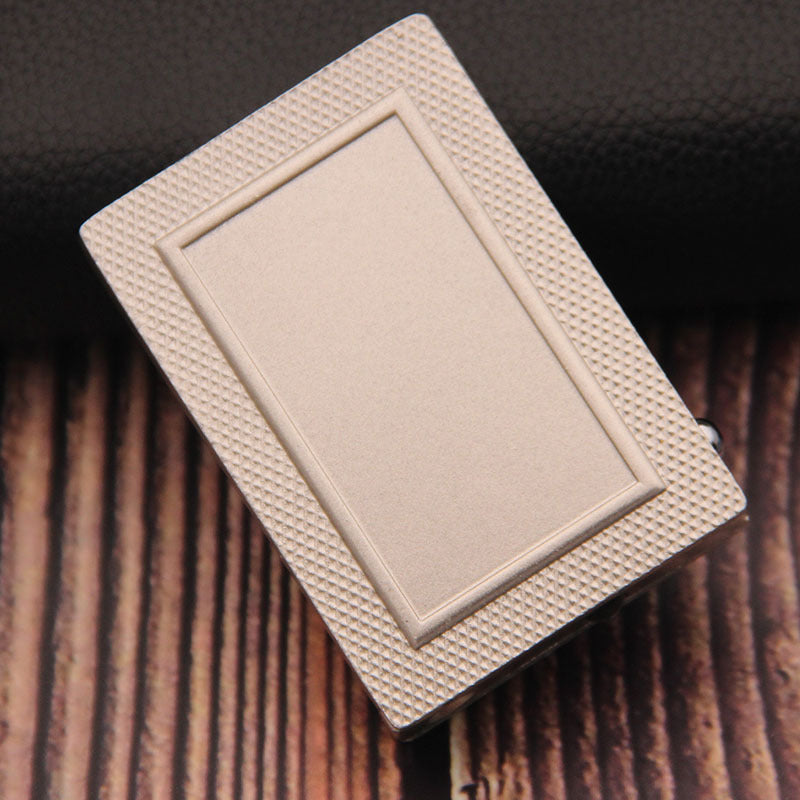 A rectangular, gold-toned metal lighter with a textured, cross-hatched border and a smooth, minimalist center panel.