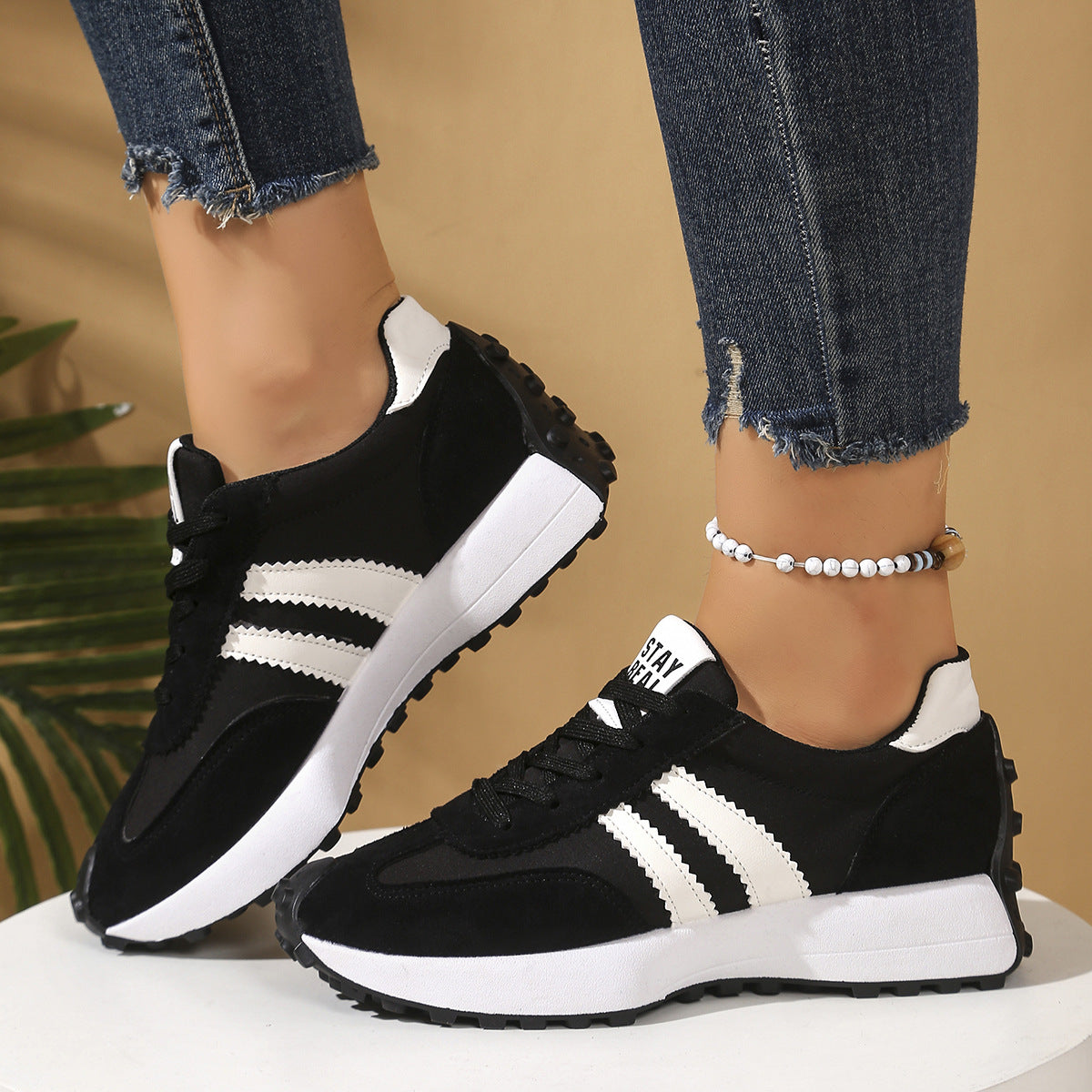 Black and white lace-up sneakers with a thick platform sole, suede-like texture, and signature side stripes.