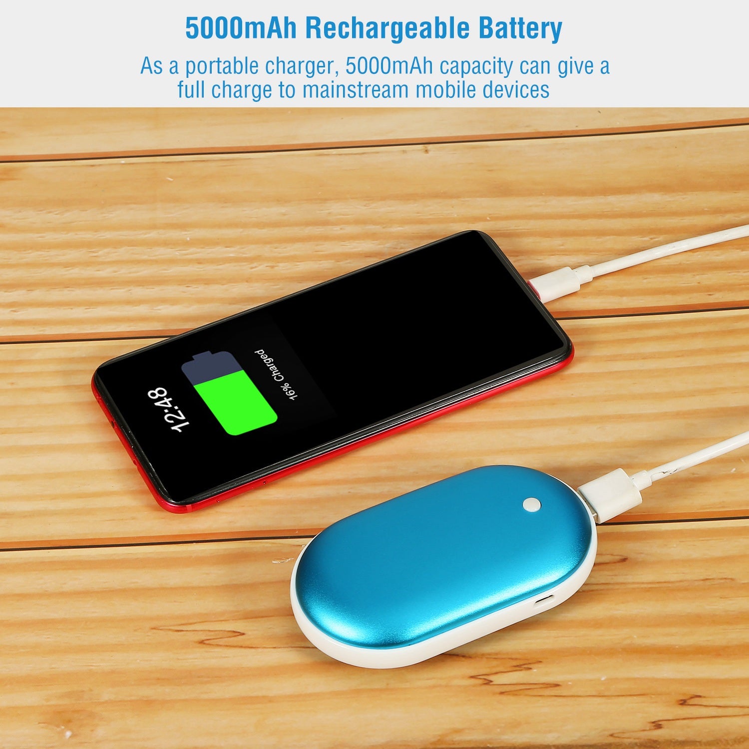 A metallic blue, oval-shaped hand warmer power bank charging a smartphone on a wooden surface.
