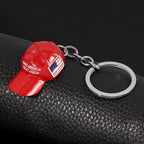 Red metal hat keychain featuring "MAKE AMERICA GREAT AGAIN" and a US flag motif, attached to a silver metal keyring.