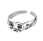 Silver adjustable ring featuring a heart-shaped face with engraved black "crying" face design and teardrop accents.