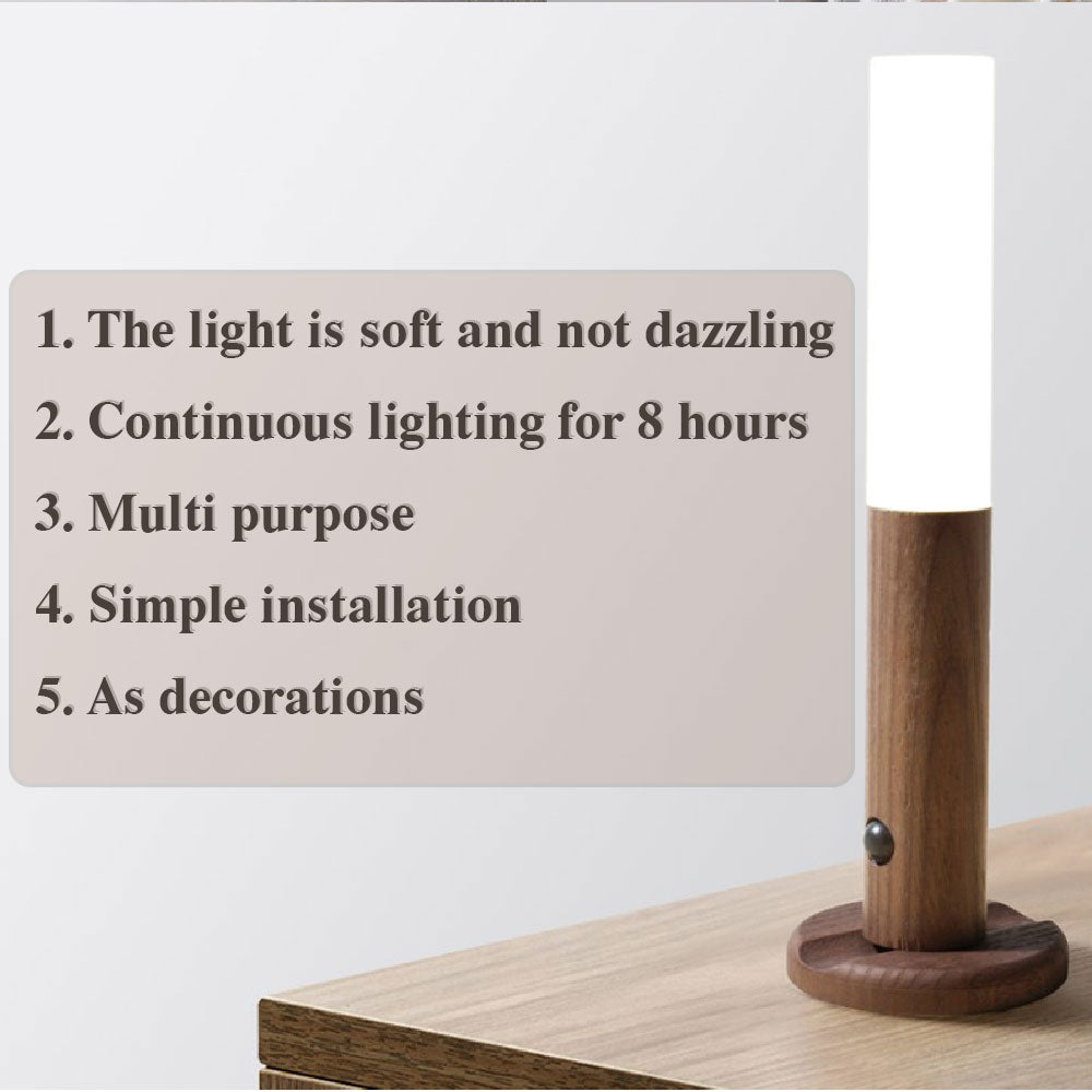Cylindrical wooden LED motion sensor lamp with a soft white light, resting on a round base on a wooden surface.