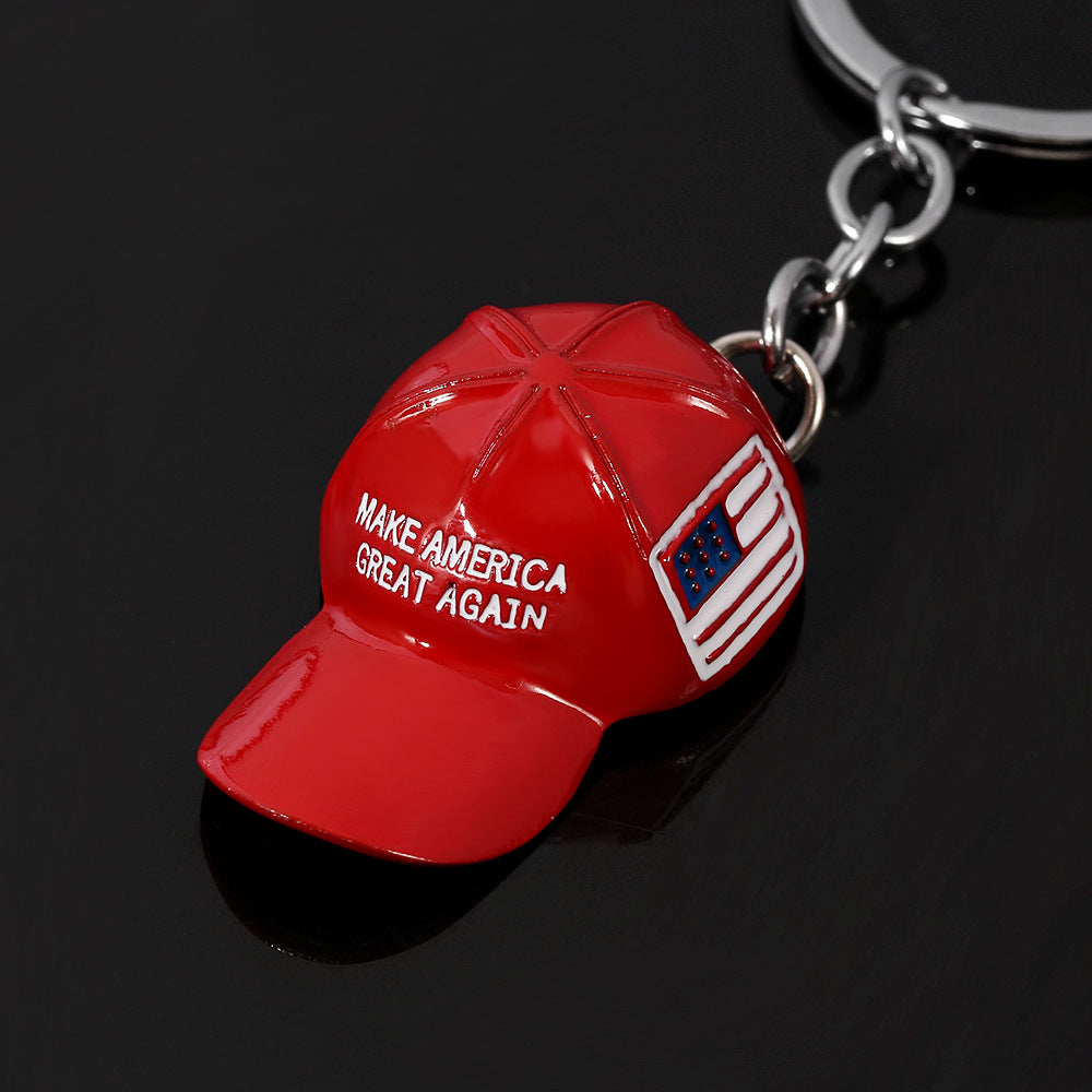 Red metal keychain shaped like a "Make America Great Again" baseball cap with a flag detail and silver keyring.