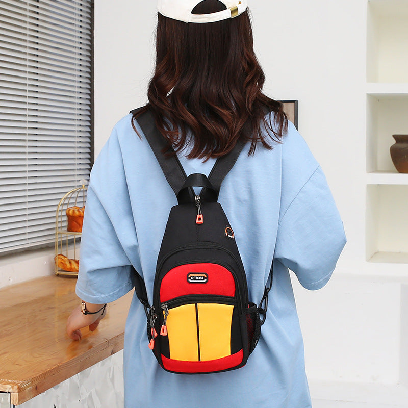 A woman wears a black, red, and yellow multi-pocket backpack with a USB port feature on her back.