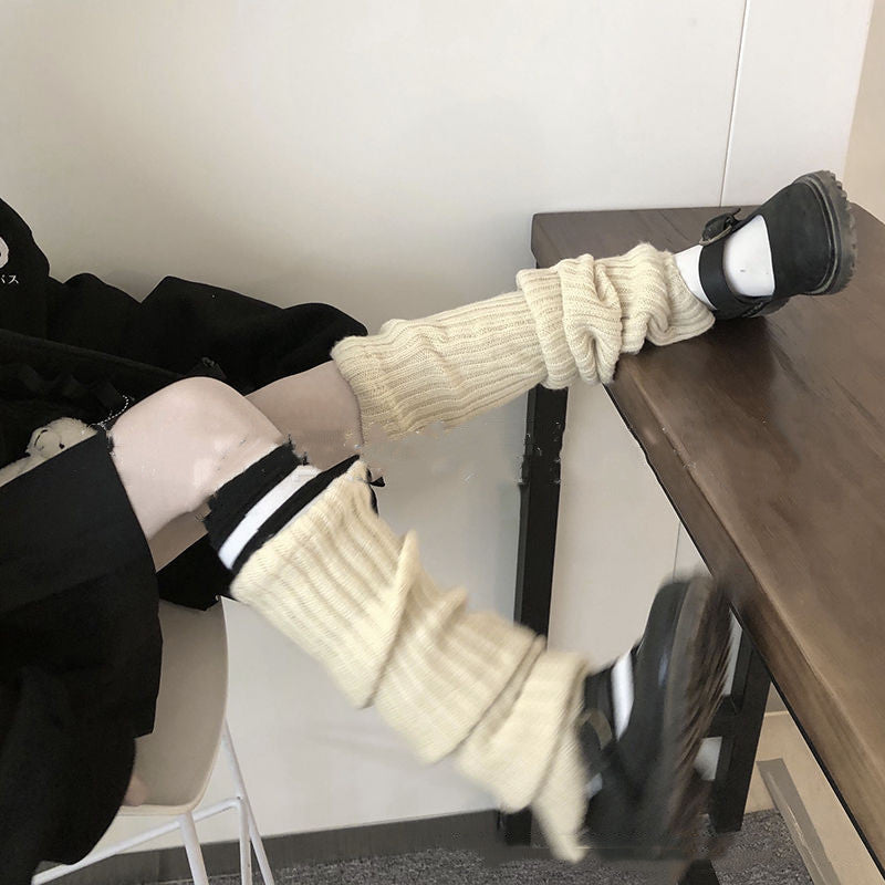 Cream-colored ribbed knit leg warmers worn over dark shoes and socks, creating a slouchy, layered style.