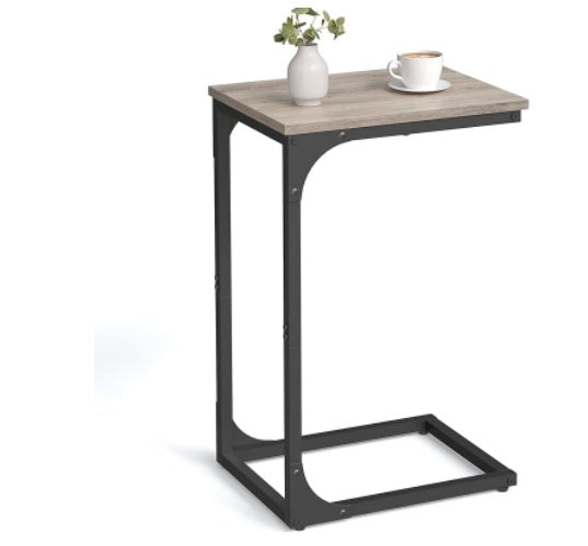 C-shaped side table with a grey wood-grain top and black metal frame, holding a small vase and a white coffee cup.