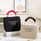 Black and beige cosmetic travel bags with "A WONDERFUL JOURNEY" text, pearl accents, and colorful top handles.