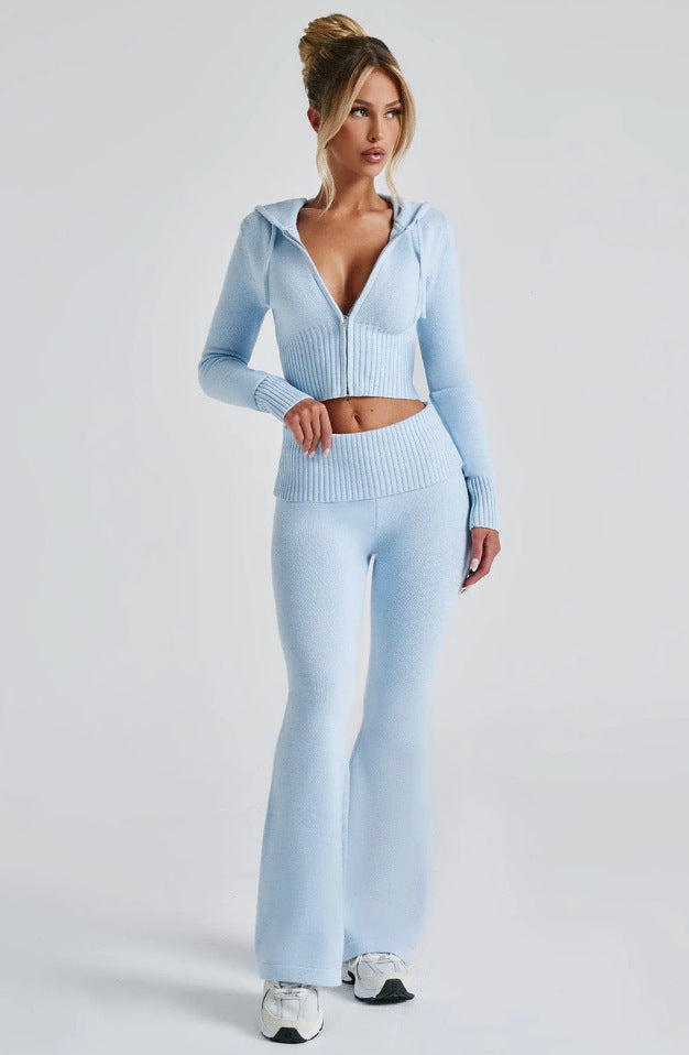 Model wears a slim-fit, powder blue knit set with a cropped, zip-up hooded jacket and matching high-waisted flare pants.