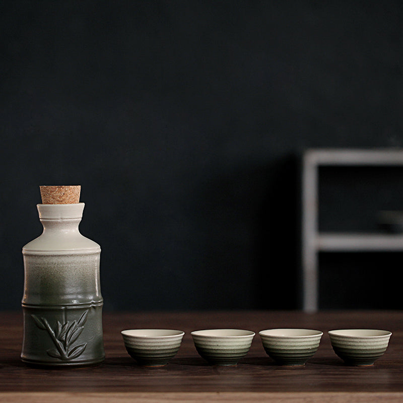 A ceramic sake set with a green-to-white ombre finish, featuring a bamboo-patterned bottle with a cork stopper and cups.