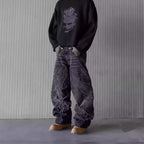 Baggy black washed denim jeans featuring frayed flame-shaped patchwork detailing and a hip-hop aesthetic.