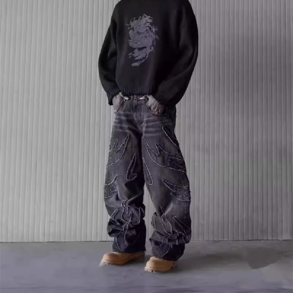 Baggy black washed denim jeans featuring frayed flame-shaped patchwork detailing and a hip-hop aesthetic.