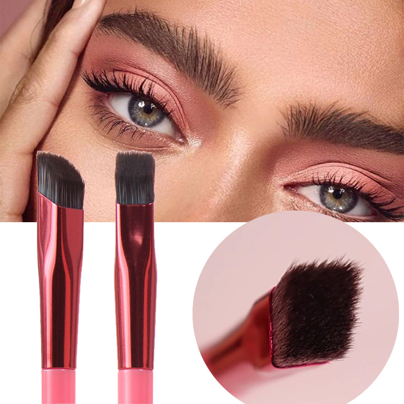 Two angled brow brushes with metallic red ferrules and pink handles against a background showing defined eyebrows.