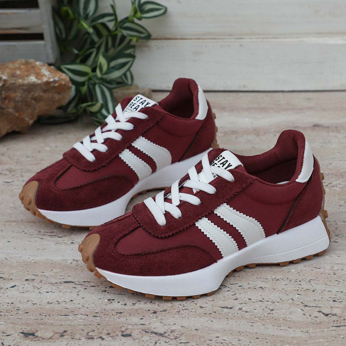 Maroon suede lace-up sneakers with white stripes, thick white midsoles, and brown rubber traction outsoles.