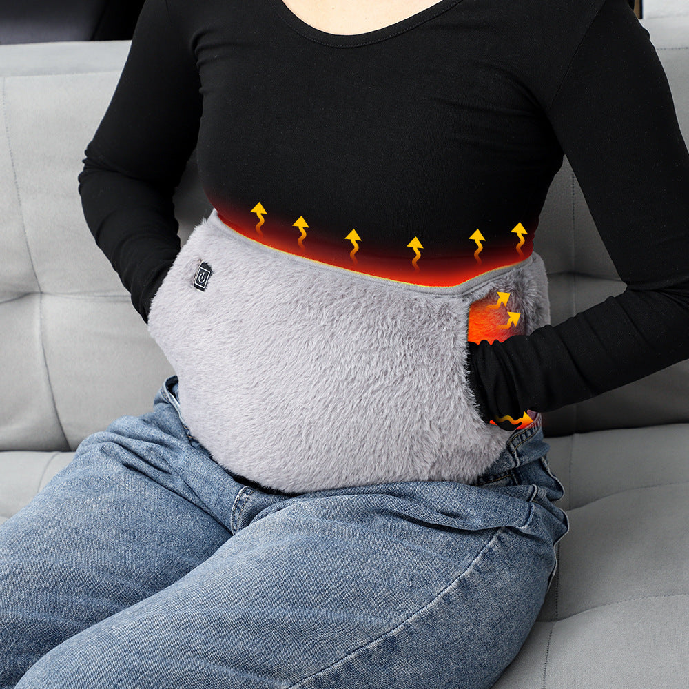 A person wears a grey, plush electric heating stomach belt with a power button, showing heat diffusion graphics.