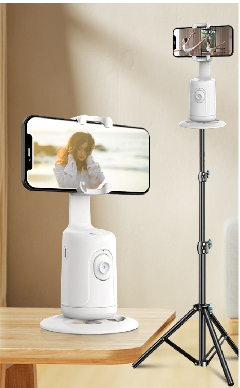White 360-degree auto face-tracking gimbal for smartphones, shown on a table and an adjustable black tripod stand.