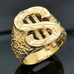 Gold-toned hip hop dollar sign ring with a textured, hammered band design, set against a dark, reflective background.