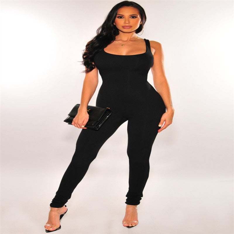 A woman wears a black, sleeveless, form-fitting exercise jumpsuit with a scoop neckline and long, slim-fit legs.