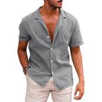 A man wearing a short-sleeve, gray button-down camp shirt in a lightweight linen-blend fabric with a notched collar.