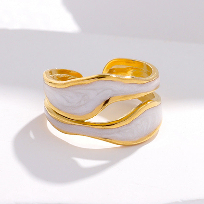 Gold-tone titanium steel open ring with a wavy white marble-effect inlay on a white background.