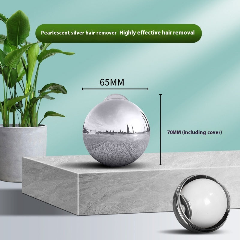 Pearlescent silver, spherical, washable sticky gel lint roller for pet hair removal on a marble-textured surface.
