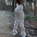 Cream-colored high-waisted cargo pants with side pockets, worn with white sneakers in an outdoor forest setting.