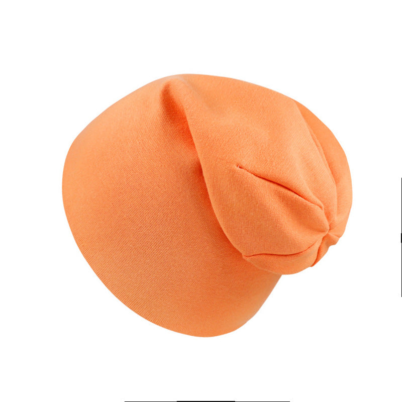 A soft, solid orange newborn cotton beanie cap with a simple, relaxed, rounded design on a plain white background.