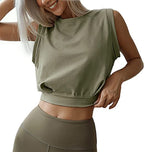 A woman wearing an olive green, sleeveless, loose-fit cotton crop top with a crew neck, paired with matching leggings.