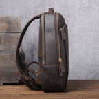 Side view of a brown vintage leather backpack with gold zippers, padded straps, and visible stitched detailing.