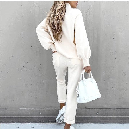 Woman wearing a beige long-sleeve fleece sweater set with matching pants, white sneakers, and a white handbag.