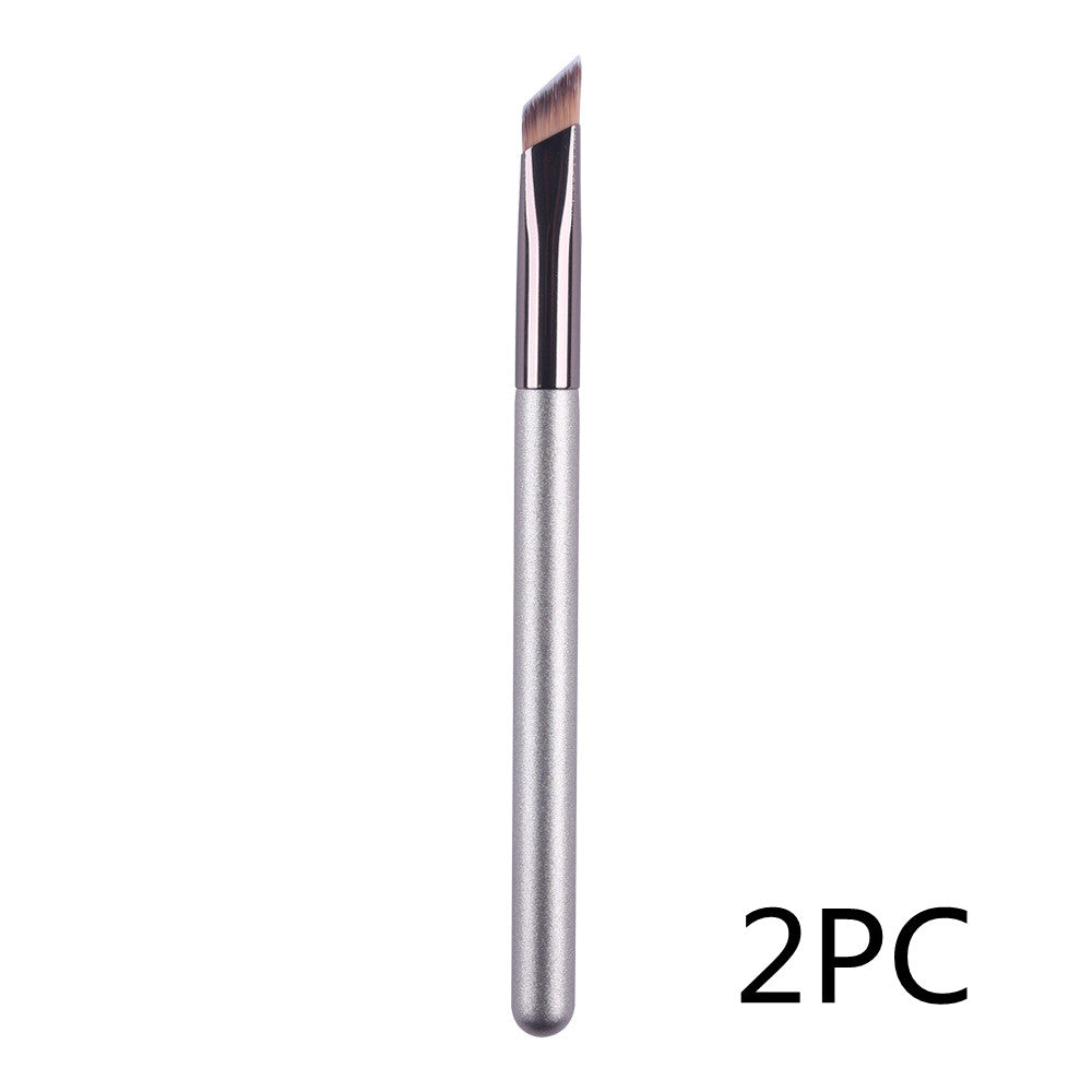 An angled eyebrow brush with a sleek silver handle and dark brown bristles, designed for precision makeup application.
