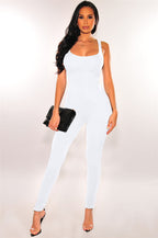 Model wears a form-fitting, sleeveless white casual exercise jumpsuit with a scoop neckline.