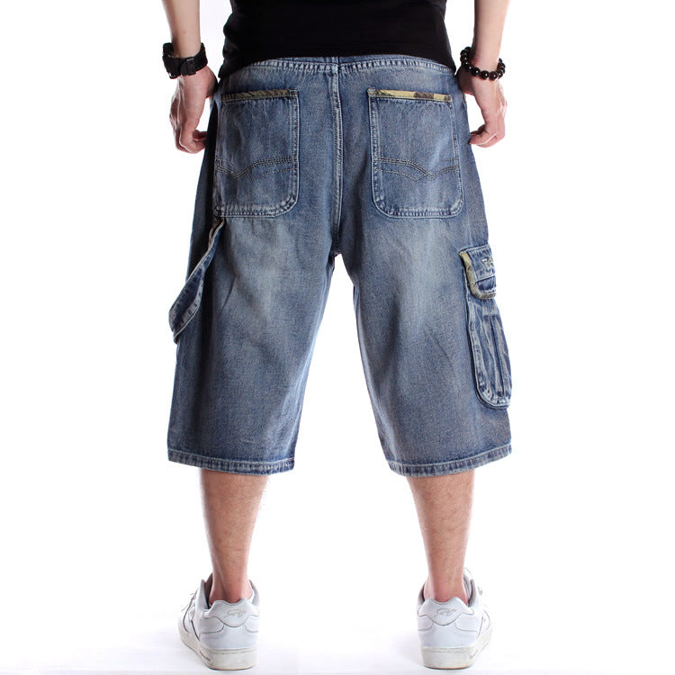 Back view of baggy blue denim hip-hop cargo shorts with multiple pockets and camo accents on a white background.