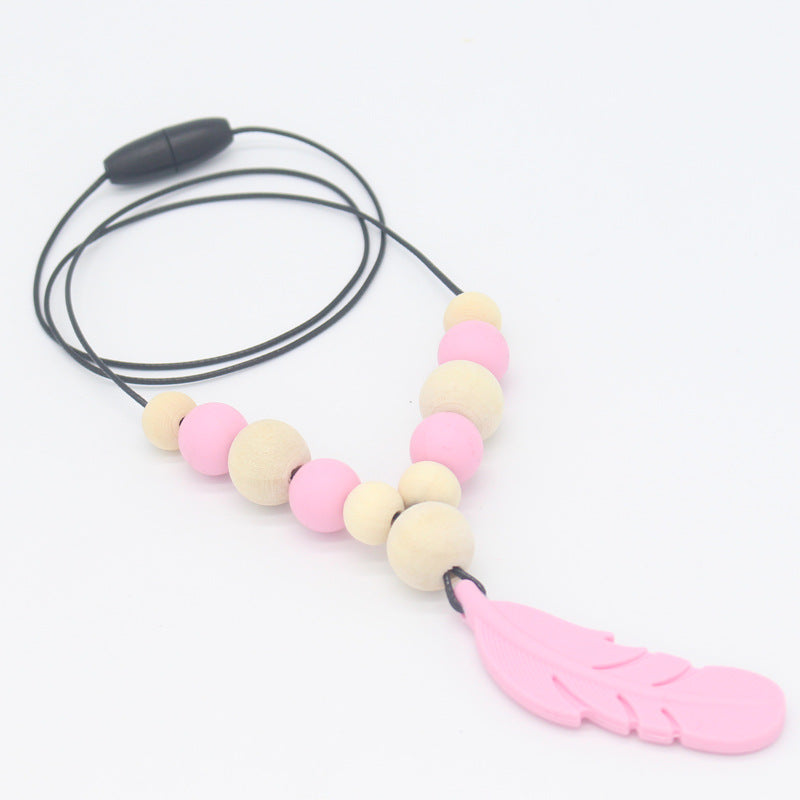 Baby teether necklace with pink silicone feather, alternating wood and pink beads on a black cord with safety clasp.