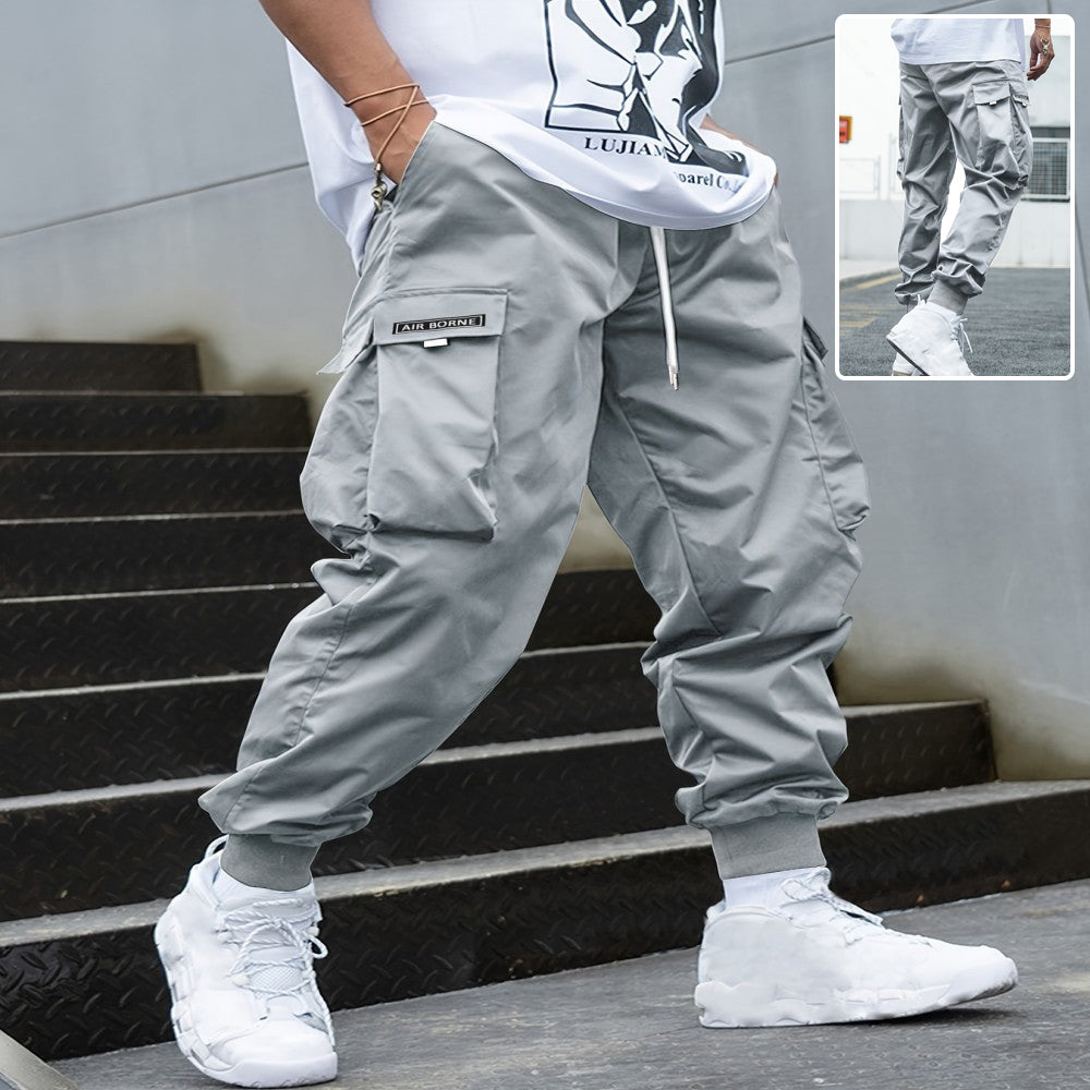 Men's grey cargo jogger pants featuring a drawstring waist, multiple utility pockets, and ribbed cuffs.