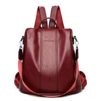 Maroon soft leather women’s travel backpack with vertical stitching, kangaroo logo, and adjustable nylon shoulder straps.
