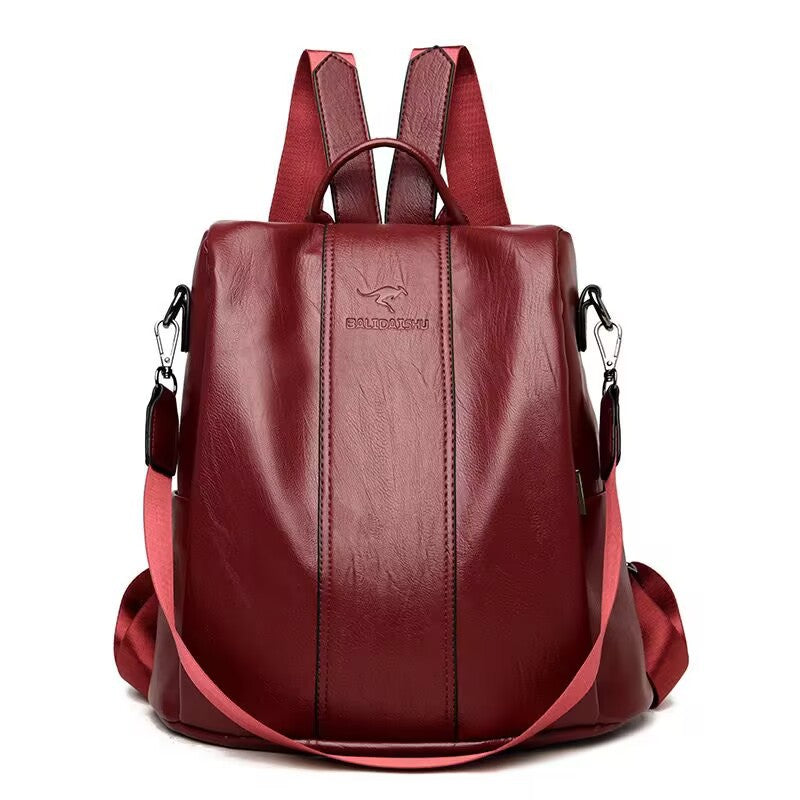 Maroon soft leather women’s travel backpack with vertical stitching, kangaroo logo, and adjustable nylon shoulder straps.