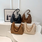 Four vintage PU leather shoulder bags in black, dark brown, tan, and cream, featuring slouchy designs and gold hardware.