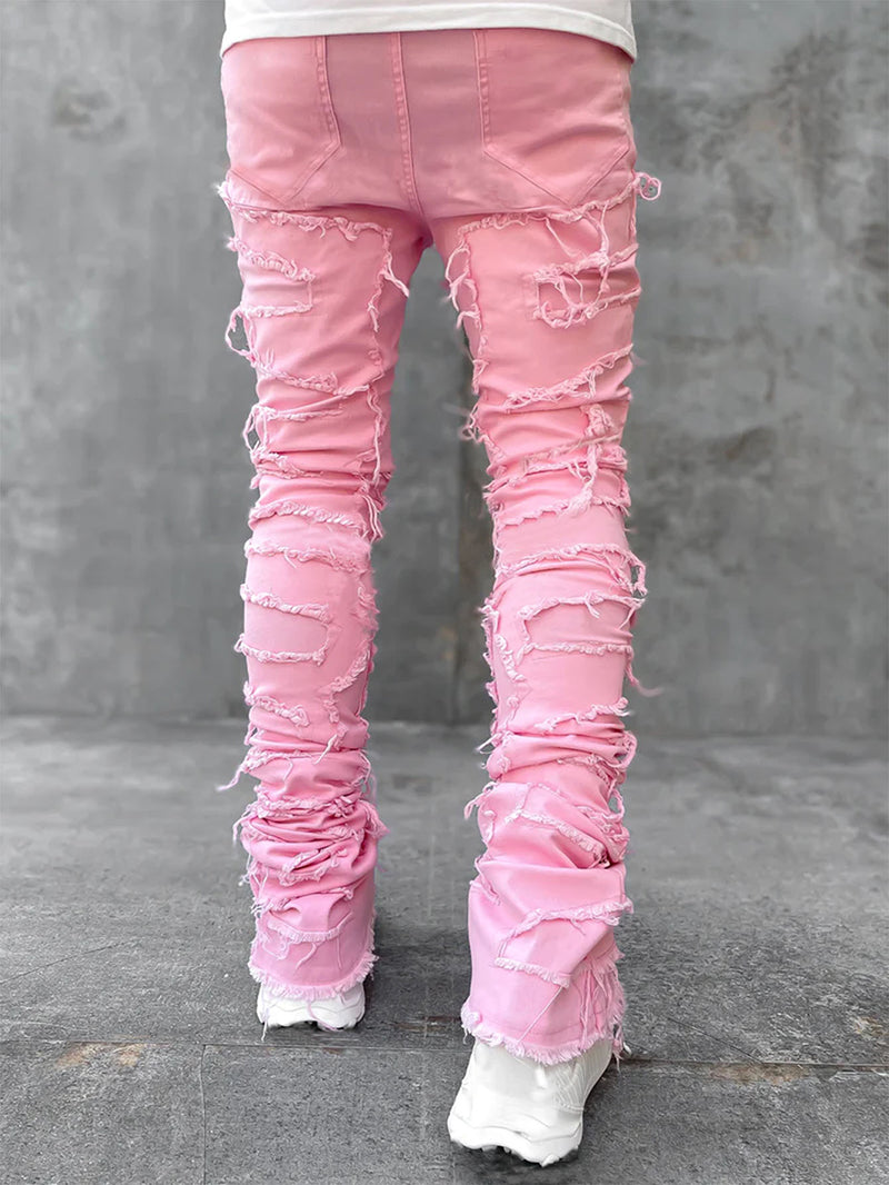 Back view of pink, tight-fit, stacked denim jeans featuring heavy distressing and frayed ripped details.