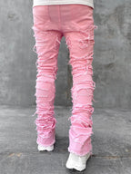 Back view of pink, tight-fit, stacked denim jeans featuring heavy distressing and frayed ripped details.