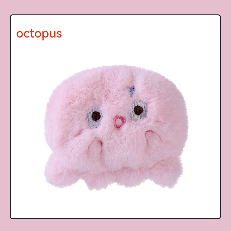 A fluffy, light pink plush octopus hand warmer with embroidered eyes and a small mouth. The word "octopus" is printed.
