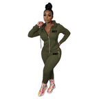 A woman wears an olive green zip-up hooded tracksuit with "BODY" printed in black, featuring pink zipper details.