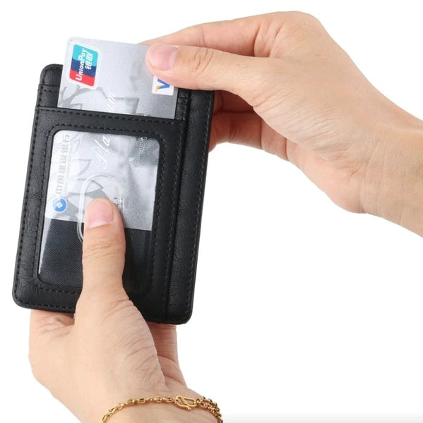 Hands holding a black slim PU leather RFID-blocking credit card holder with a clear ID window slot.