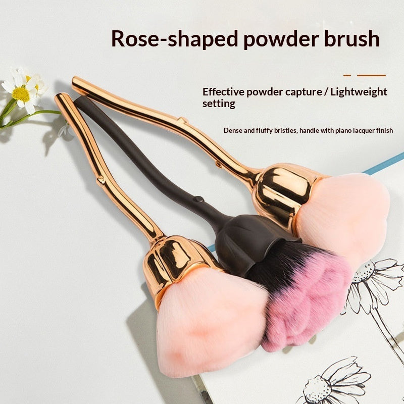 Two rose-shaped makeup brushes with metallic/matte handles and fluffy, dense pink and black bristles.