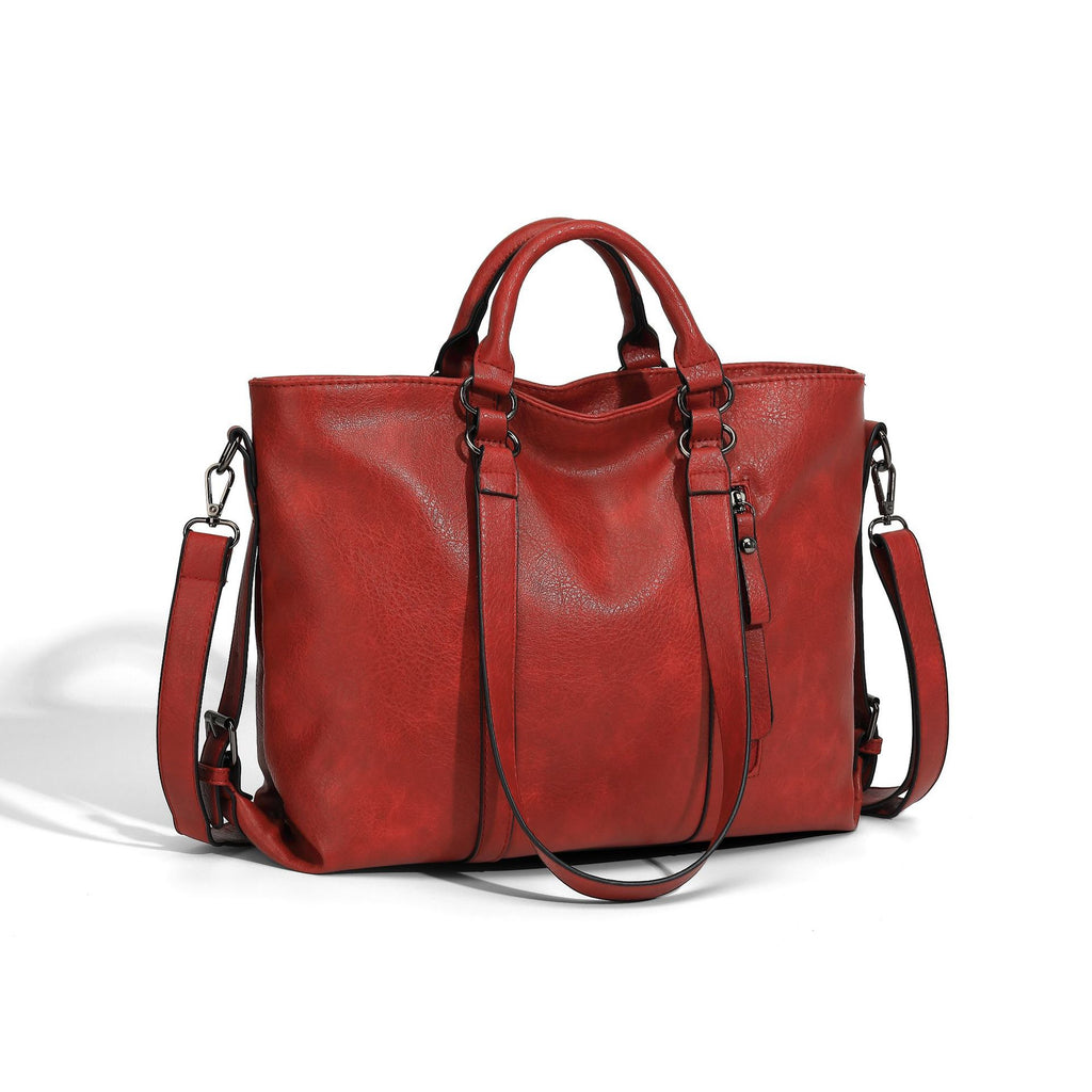 Large red soft leather tote bag with dual handles, detachable shoulder strap, and side zipper against white background.