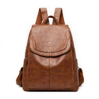 Brown faux leather backpack with a flap top, top handle, adjustable fabric straps, and embossed kangaroo logo.