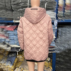 Back view of a dusty pink, quilted hooded jacket with a black drawstring, shown on a mannequin in a warehouse.