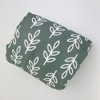 Soft, dark green cotton baby nursing arm pillow featuring a white leaf pattern for comfortable infant breastfeeding.
