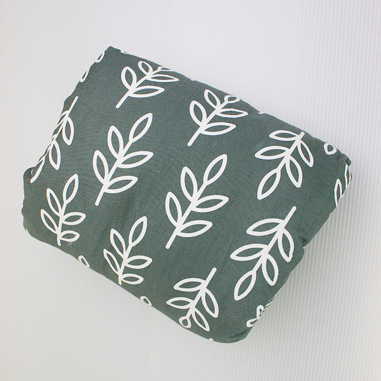 Soft, dark green cotton baby nursing arm pillow featuring a white leaf pattern for comfortable infant breastfeeding.