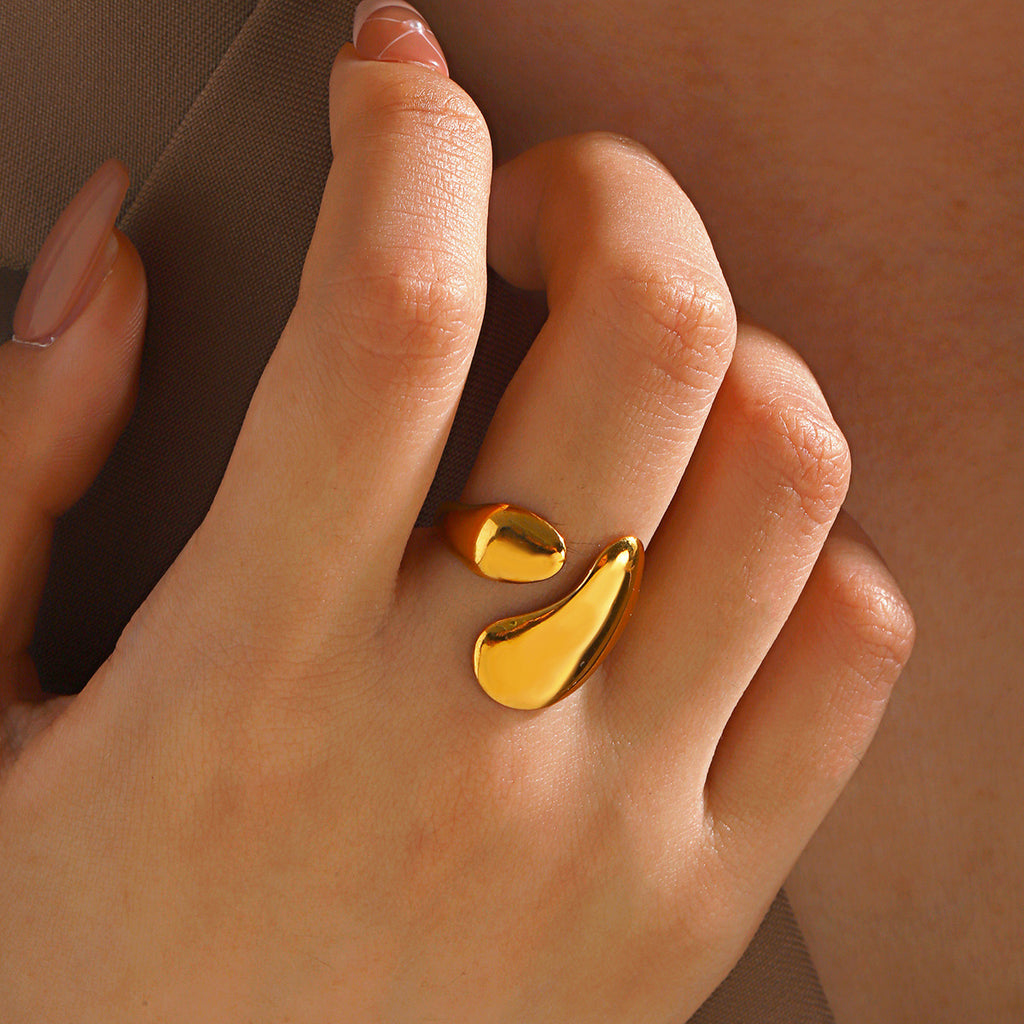 Gold-toned, stainless steel open ring featuring two smooth, abstract teardrop-shaped ends on a finger.